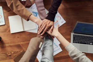 Team members joining hands together over business planning documents