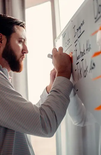 Man writing on a white board and brainstorming ideas with sticky notes
